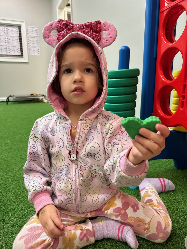 Child holding a green toy heart.