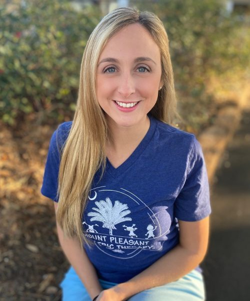 Smiling person in blue shirt outdoors.