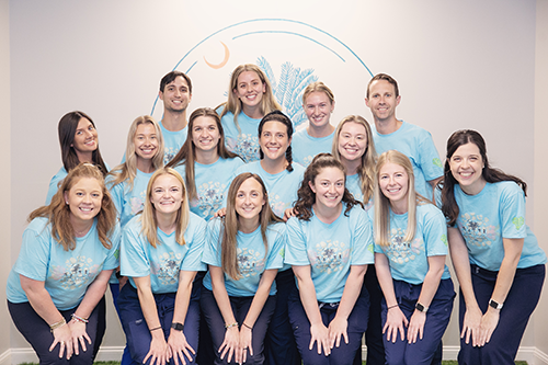 Group photo of smiling people in blue shirts.