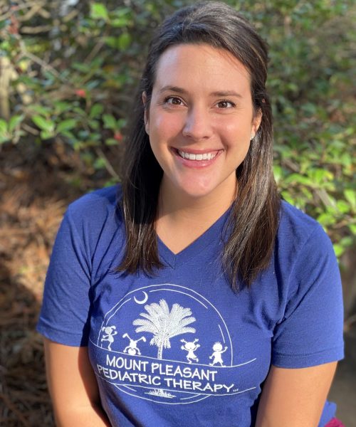 Smiling woman in blue shirt outdoors.