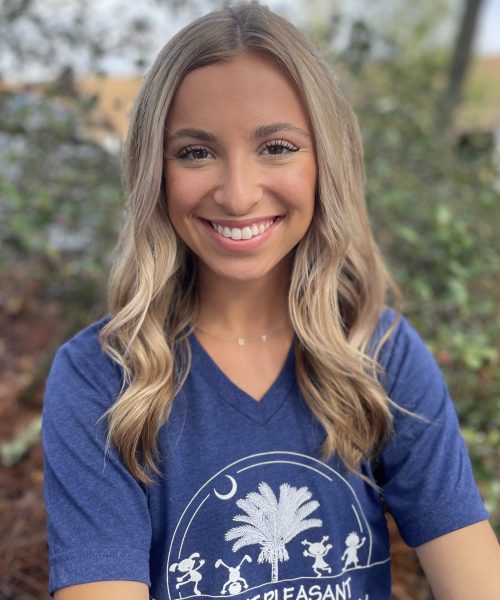 Smiling woman outdoors wearing a blue shirt.