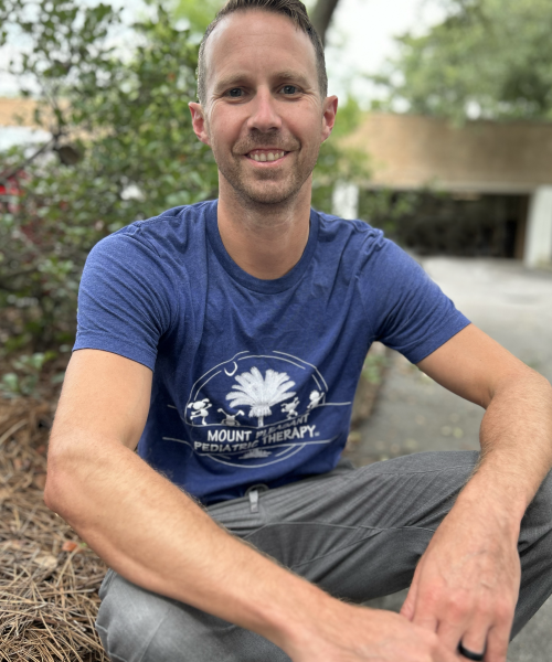 Man sitting outdoors wearing a blue shirt.