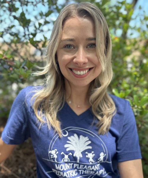Smiling woman outdoors with green background.