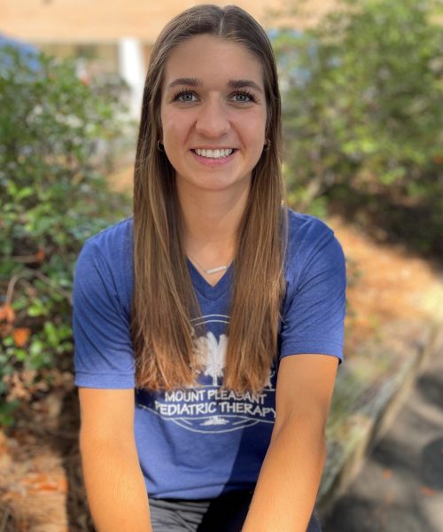 Smiling woman outdoors wearing a blue shirt.