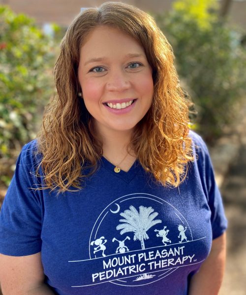 Smiling person in blue therapy shirt outdoors.
