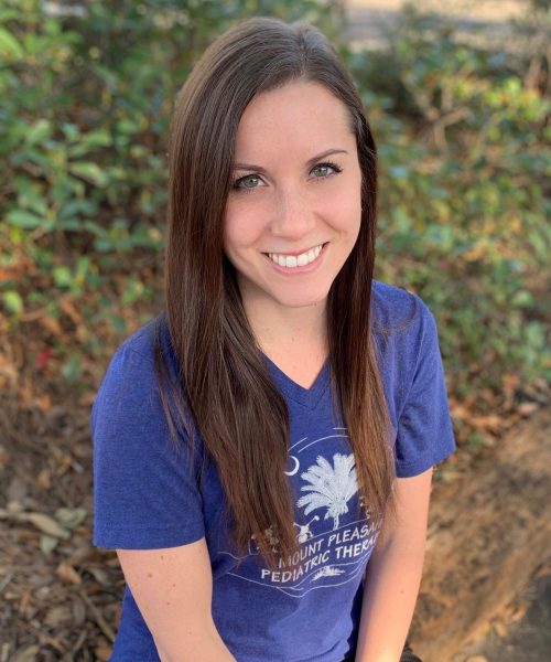 Smiling woman in blue shirt outdoors.