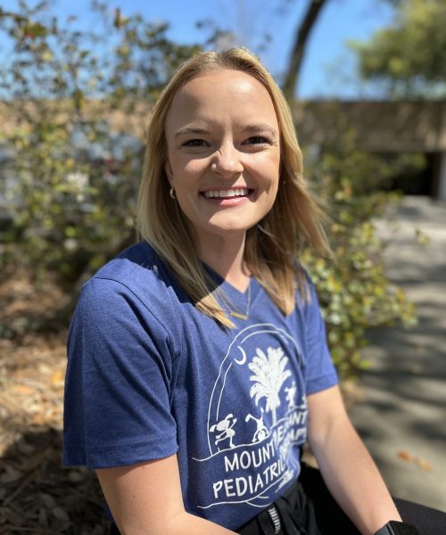 Smiling woman sitting outdoors in blue shirt.