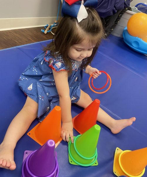 Toddler playing with colorful cones and rings.