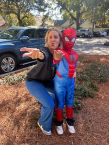 Woman with child in Spider-Man costume outside.