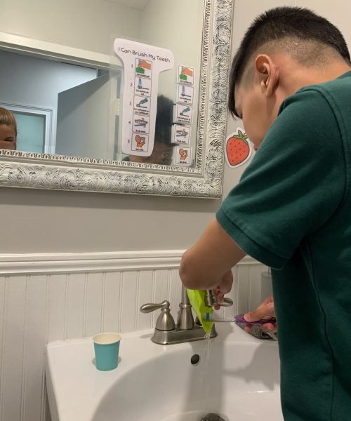Child brushing teeth at bathroom sink.