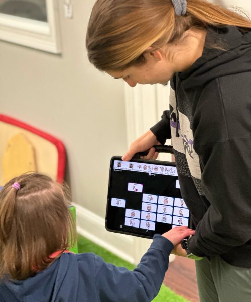 Child and adult using communication tablet together.