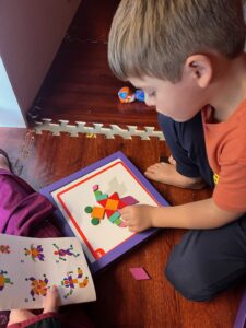 Child assembling colorful geometric puzzle pieces.