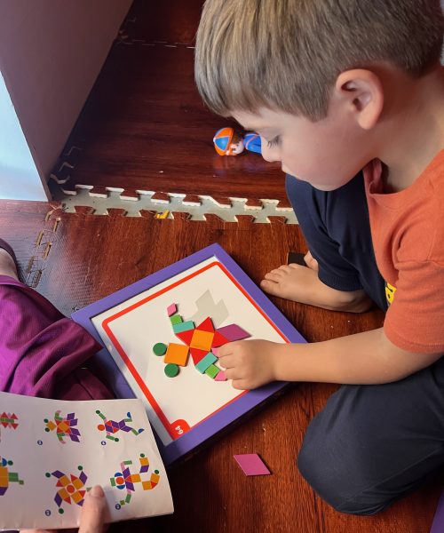 Child solving geometric puzzle on the floor.