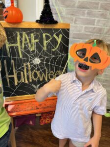 Child in pumpkin mask celebrating Halloween.