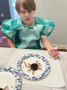 Child in costume making cookie spider craft.