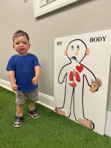 Child standing beside body diagram poster.