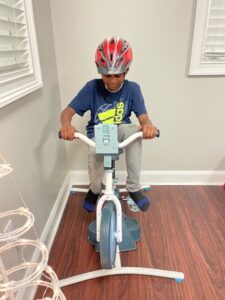 Child riding stationary exercise bike indoors.