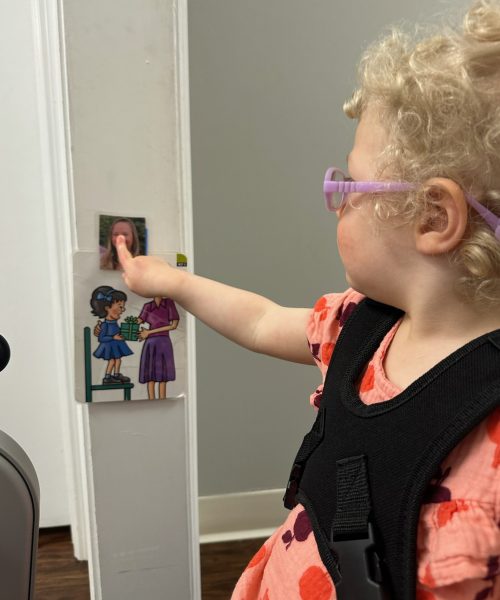 Child pointing at colorful wall sticker.