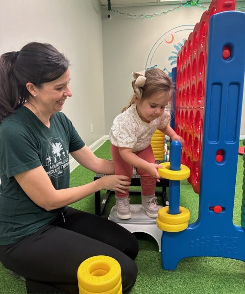 Child playing giant Connect Four with adult.