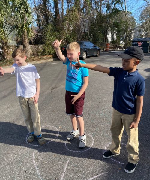 Three boys playing outside with chalk circles.