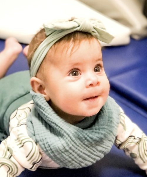 Smiling baby with headband and bib.