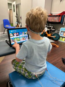 A child playing a video game on a tablet while wearing headphones.