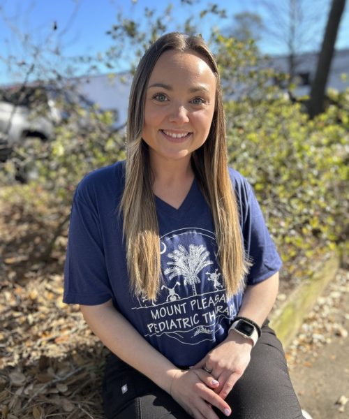 A smiling woman outdoors wearing a navy blue Mount Pleasant Patriots t-shirt.